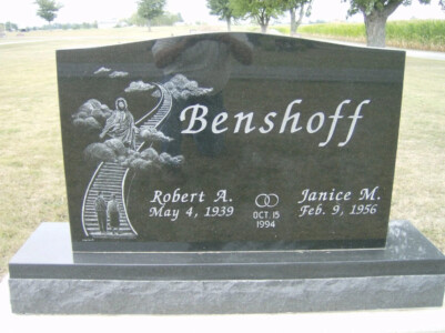 Baxter cross headstone monument with engraved inscription and decorative granite base in cemetery setting